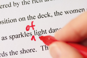 Hand with Red Pen Proofreading Text Closeup